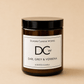 An amber glass jar candle with a black lid and a white label reading 'Dundee Candle Works DCW Earl Grey & Verbena Scented Candle' on a warm beige background.