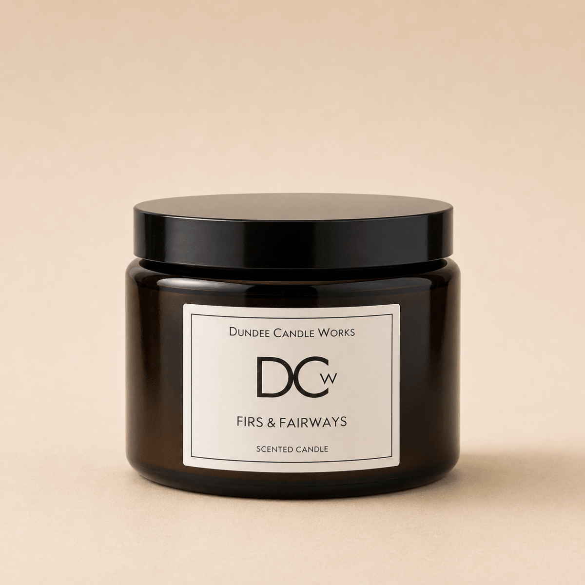 A dark amber glass jar candle with a black lid and a white label reading 'Dundee Candle Works DCw Firs & Fairways Scented Candle' on a warm beige background.