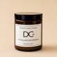 An amber glass jar candle with a black lid and a white label reading 'Dundee Candle Works DCW Marmalade Gingerbread Scented Candle' on a warm beige background.