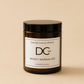 A single amber glass jar candle with a black lid and a white label reading 'Dundee Candle Works DCw Whisky Marmalade Scented Candle' on a warm beige background.