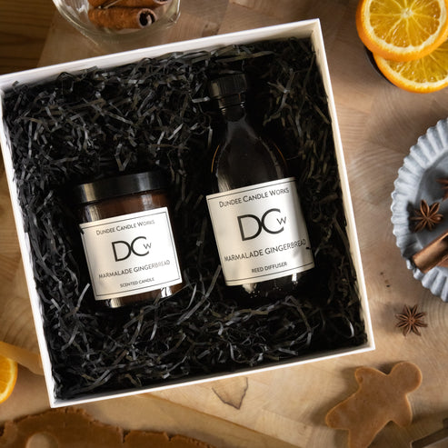 Marmalade Gingerbread gift set with candle and diffuser from Dundee Candle Works on a wooden surface surrounded by uncooked gingerbread and spices.