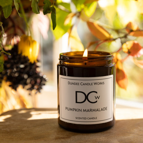 Candle labeled 'Dundee Candle Works Pumpkin Marmalade' with a blurred natural background